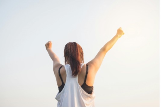 Photo of a woman raising both arms up.